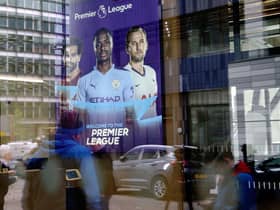 Members of the media are reflected in the glass at the headquarters of the English Premier League in London on March 13, 2020.