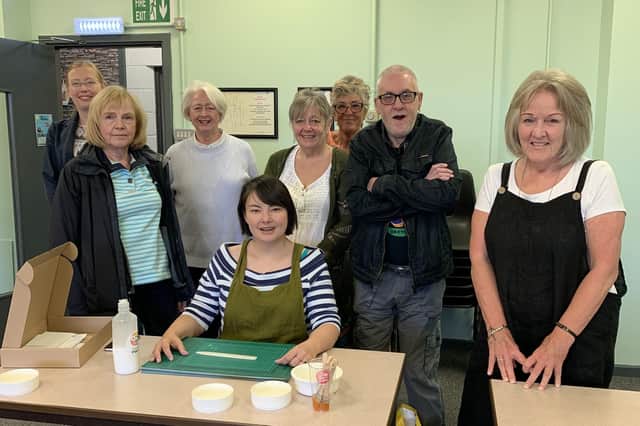 Artist Yvette Ja, seated, leads one of Angela’s class in a bookbinding workshop.