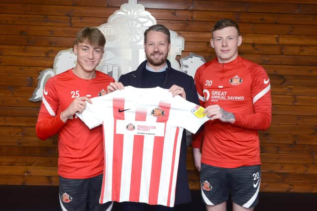 SAFC players Jack Clarke and Anthony Patterson holding the special edition Foundation of Light shirt alongside Great Annual Savings Group’s operations director Craig Shields.