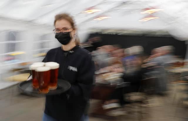 A waitress carries pints under a marquee on Monday, April 12, 2021 (AP Photo/Frank Augstein)