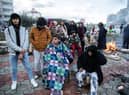 Earthquake survivors sit around a fire in Iskenderun Turkey