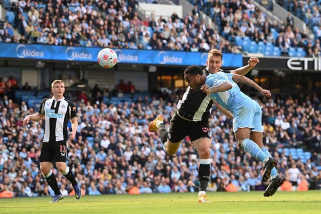 Manchester City player Raheem Sterling beats the challenge of Newcastle defender Dan Burn to head in the opening city goal during the Premier League match between Manchester City and Newcastle United at Etihad Stadium on May 08, 2022 in Manchester, England. (Photo by Stu Forster/Getty Images)
