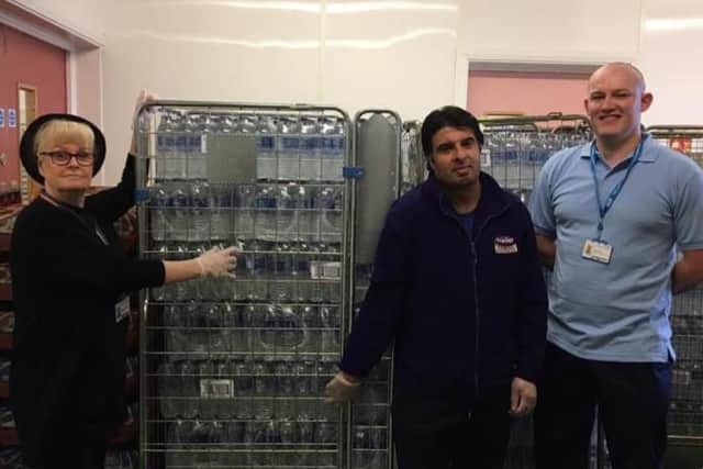 Shopkeeper Taz Ali (centre) donates crates of bottled water to NHS staff.
