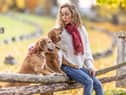 A young woman sits in the park with her dogs and shows them love (photo: Adobe)