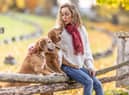 A young woman sits in the park with her dogs and shows them love (photo: Adobe)