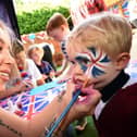 2 year old Noah Cutting has his face painted by Jade Benton from "Brush Hour"