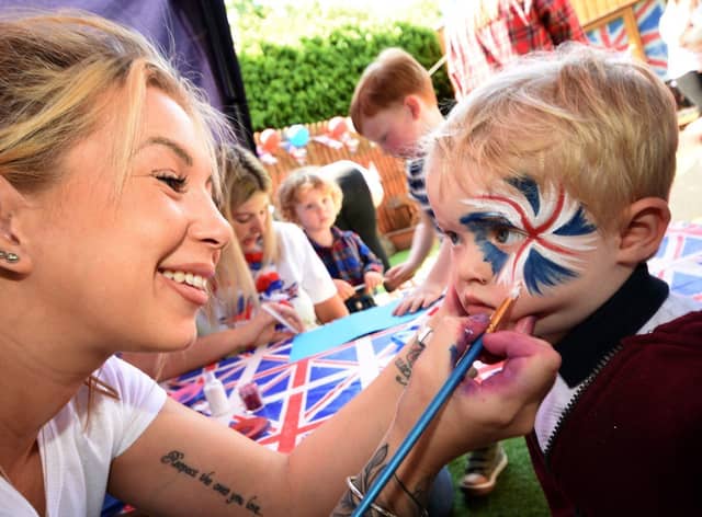 2 year old Noah Cutting has his face painted by Jade Benton from "Brush Hour"