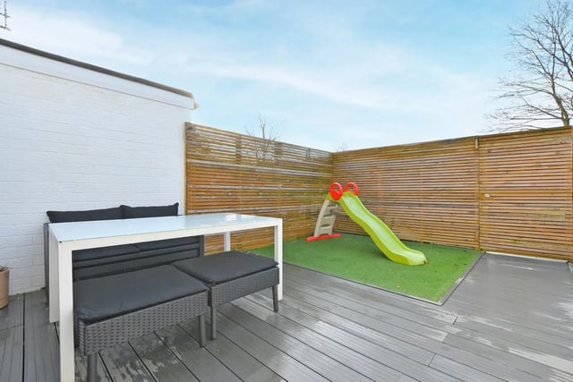 The garden is laid in grey composite decking with a small artificial grass area.