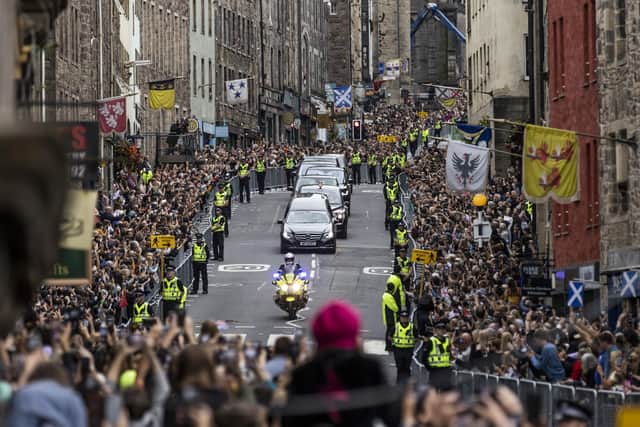 Members of the public gather on the Royal Mile in Edinburgh to watch the hearse carrying the coffin of Queen Elizabeth II, draped with the Royal Standard of Scotland, as it completes its journey from Balmoral to the Palace of Holyroodhouse in Edinburgh, where it will lie in rest for a day. Picture date: Sunday September 11, 2022.