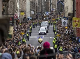 Members of the public gather on the Royal Mile in Edinburgh to watch the hearse carrying the coffin of Queen Elizabeth II, draped with the Royal Standard of Scotland, as it completes its journey from Balmoral to the Palace of Holyroodhouse in Edinburgh, where it will lie in rest for a day. Picture date: Sunday September 11, 2022.