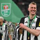 Newcastle United's English defender Dan Burn celebrates with the trophy on the pitch