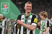 Newcastle United's English defender Dan Burn celebrates with the trophy on the pitch