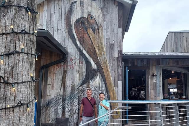 Artist Kelly Pierre with some of his work on the wall of the East Pass restaurant