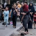 TOPSHOT - Palestinian women with their children fleeing from their homes following Israeli air strikes rush along a street in Gaza City on October 11, 2023. At least 30 people have been killed and hundreds wounded as Israel pounded the Gaza Strip with hundreds of air strikes overnight, a Hamas government official said on October 11. Israel declared war on Hamas on October 8 following a shock land, air and sea assault by the Gaza-based Islamists. (Photo by MOHAMMED ABED / AFP) (Photo by MOHAMMED ABED/AFP via Getty Images)