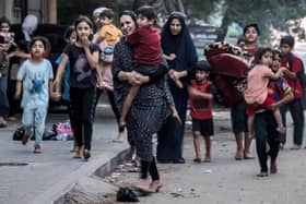 TOPSHOT - Palestinian women with their children fleeing from their homes following Israeli air strikes rush along a street in Gaza City on October 11, 2023. At least 30 people have been killed and hundreds wounded as Israel pounded the Gaza Strip with hundreds of air strikes overnight, a Hamas government official said on October 11. Israel declared war on Hamas on October 8 following a shock land, air and sea assault by the Gaza-based Islamists. (Photo by MOHAMMED ABED / AFP) (Photo by MOHAMMED ABED/AFP via Getty Images)