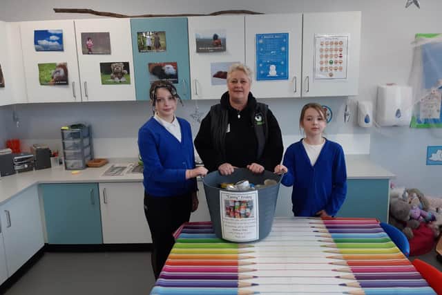 Pupils Maddie Waite, 10, and Ruby Bellingham, seven, handing over one of four large buckets of donated items to Jo Durkin from Hebburn Helps.