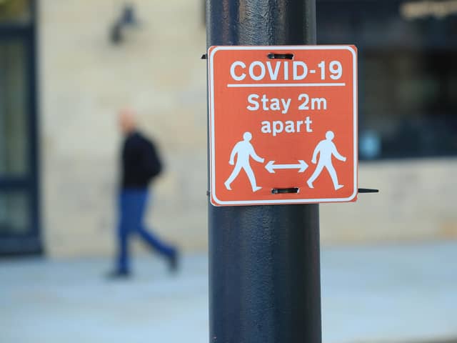 File photo of a sign advising people to stay two metres apart on a lamppost
