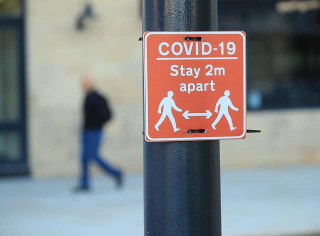 File photo of a sign advising people to stay two metres apart on a lamppost