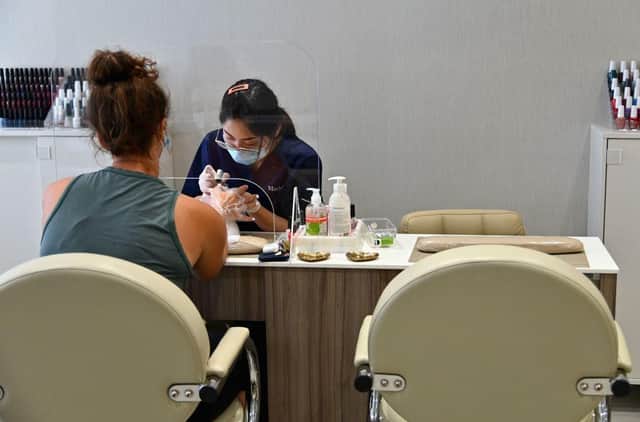 A client receives a manicure at a nail salon. Salons are allowed to reopen in England from today (Photo by ANGELA WEISS/AFP via Getty Images)