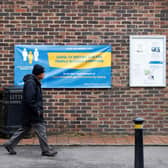 A man walks past a banner featuring a coronavirus testing site set up at St Mary's Church hall in the London borough of Hillingdon, England on May 14, 2021, as part of surge testing to monitor and suppress the spread of the Covid-19 variant first identified in India. - The Indian coronavirus variant has been detected in a number of areas in England which are reporting the highest rates of infection, data from Public Health England (PHE) suggests. (Photo by Adrian DENNIS / AFP) (Photo by ADRIAN DENNIS/AFP via Getty Images)