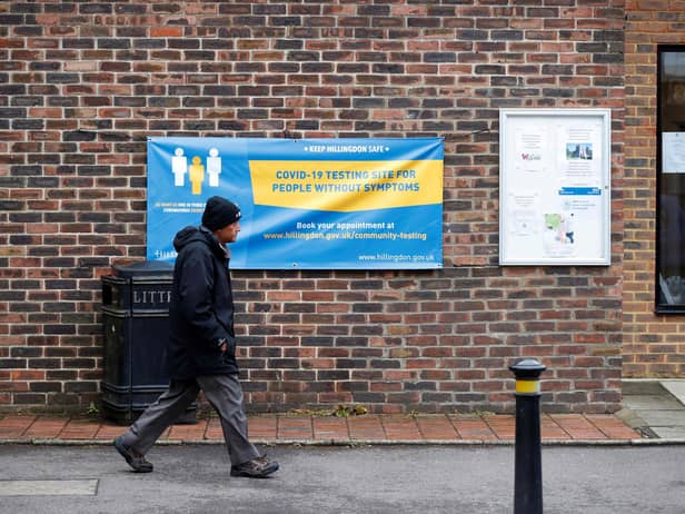 A man walks past a banner featuring a coronavirus testing site set up at St Mary's Church hall in the London borough of Hillingdon, England on May 14, 2021, as part of surge testing to monitor and suppress the spread of the Covid-19 variant first identified in India. - The Indian coronavirus variant has been detected in a number of areas in England which are reporting the highest rates of infection, data from Public Health England (PHE) suggests. (Photo by Adrian DENNIS / AFP) (Photo by ADRIAN DENNIS/AFP via Getty Images)