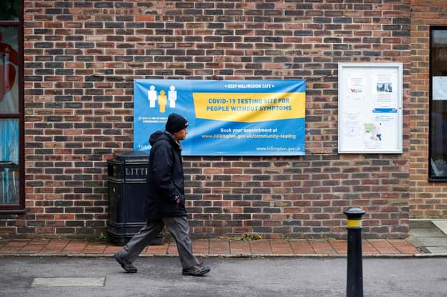 A man walks past a banner featuring a coronavirus testing site set up at St Mary's Church hall in the London borough of Hillingdon, England on May 14, 2021, as part of surge testing to monitor and suppress the spread of the Covid-19 variant first identified in India. - The Indian coronavirus variant has been detected in a number of areas in England which are reporting the highest rates of infection, data from Public Health England (PHE) suggests. (Photo by Adrian DENNIS / AFP) (Photo by ADRIAN DENNIS/AFP via Getty Images)