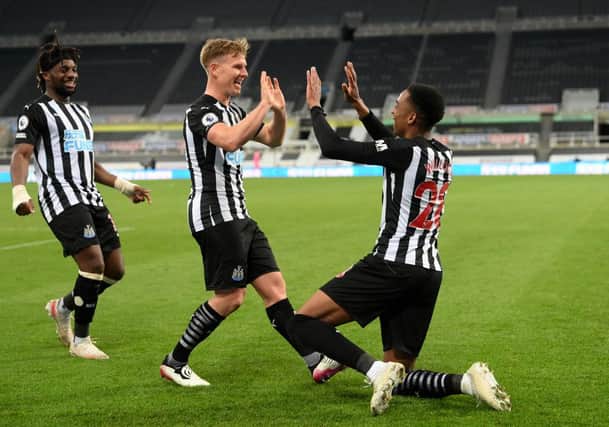 Joe Willock of Newcastle United celebrates with team mate Matt Ritchie after scoring their sides third goal, missing from the penalty spot but scoring the rebound during the Premier League match between Newcastle United and Manchester City at St. James Park on May 14, 2021 in Newcastle upon Tyne, England.
