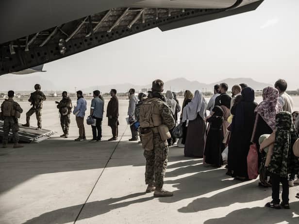In this image provided by the US Marine Corps, evacuees wait to board a Boeing C-17 Globemaster III during an evacuation at Hamid Karzai International Airport in Kabul, Afghanistan, Monday, Aug. 30. 2021. (Staff Sgt. Victor Mancilla/U.S. Marine Corps via AP)
