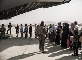 In this image provided by the US Marine Corps, evacuees wait to board a Boeing C-17 Globemaster III during an evacuation at Hamid Karzai International Airport in Kabul, Afghanistan, Monday, Aug. 30. 2021. (Staff Sgt. Victor Mancilla/U.S. Marine Corps via AP)