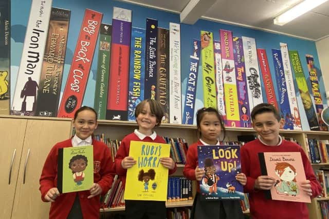 Happy pupils in front of the St Joseph's book wall