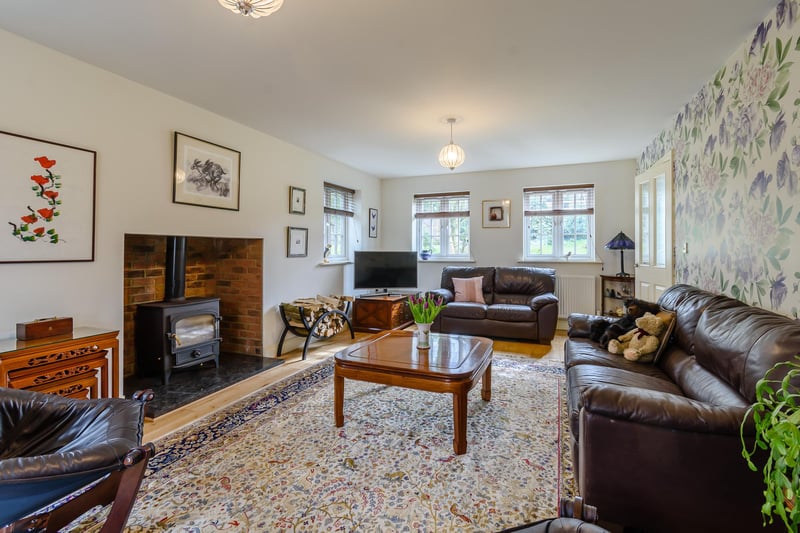 A large 24 ft sitting room with wooden flooring and a feature fireplace with wood burning stove.