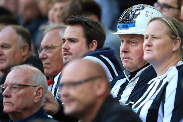 One supporter is pictured wearing a safety hat emblazoned with the Newcastle United badge (Photo by LINDSEY PARNABY/AFP via Getty Images)