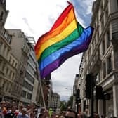A rainbow flag being held aloft.