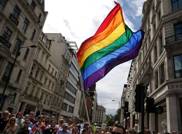 A rainbow flag being held aloft.