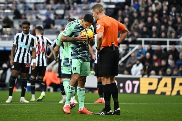 Fulham's Serbian striker Aleksandar Mitrovic (L), watched by Referee Robert Jones, kisses the match ball before taking and scoring a penalty, that was disallowed as he kicked the ball onto his standing foot,  during the English Premier League football match between Newcastle United and Fulham at St James' Park in Newcastle-upon-Tyne, north-east England on January 15, 2023. (Photo by OLI SCARFF/AFP via Getty Images)