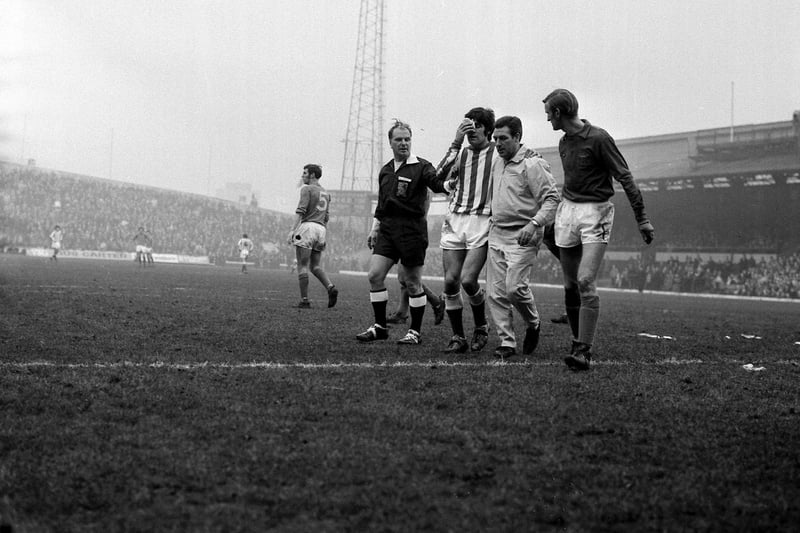 Flanked by Referee F M Nicholson and Alan Ross, Billy Hughes is led from the field by trainer-coach Billy Elliott for treatment to an injury during the January 1971 game with Carlisle United.
