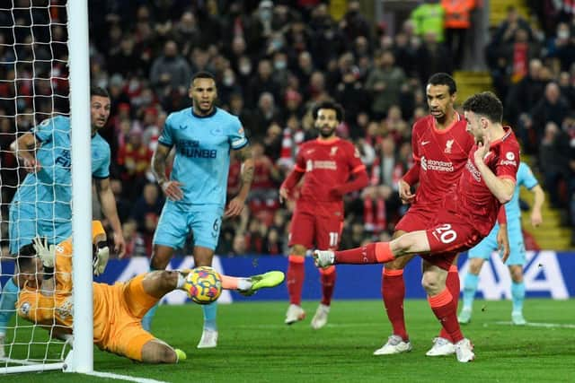 Liverpool's Portuguese striker Diogo Jota (R) shoots to score their first goal during the English Premier League football match between Liverpool and Newcastle United at Anfield in Liverpool, north west England on December 16, 2021. (Photo by OLI SCARFF/AFP via Getty Images)