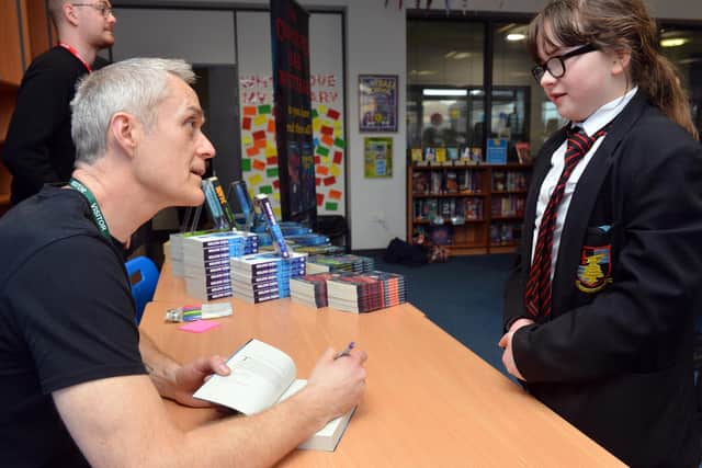 Author Dan Smith signing copies of his books for pupils.
