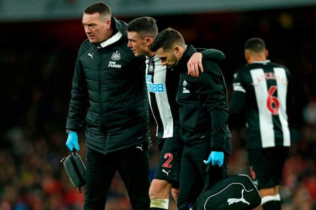 Newcastle United's Irish defender Ciaran Clark (C) is helped from the pitch after picking up an injury during the English Premier League football match between Arsenal and Newcastle United at the Emirates Stadium in London on February 16, 2020.
