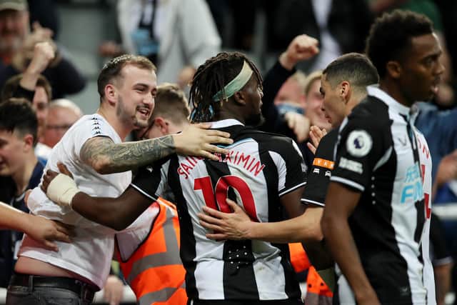 NEWCASTLE UPON TYNE, ENGLAND - SEPTEMBER 17: Allan Saint-Maximin of Newcastle United celebrates with a fan after scoring their team's first goal during the Premier League match between Newcastle United and Leeds United at St. James Park on September 17, 2021 in Newcastle upon Tyne, England. (Photo by Ian MacNicol/Getty Images)