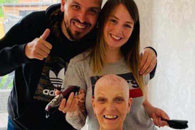 Christine Haldane has her head shaved by Hannah Craxford, her son Robert's partner, with help from her younger son Christopher.