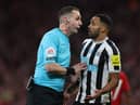 Referee David Coote speaks with Newcastle United striker Callum Wilson.