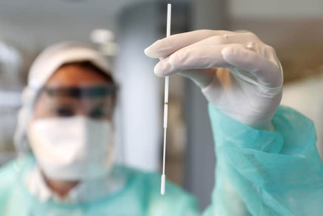 A technician shows a nasal swab during a rehearsal of a COVID-19 testing session (AP Photo/Jean-Francois Badias)