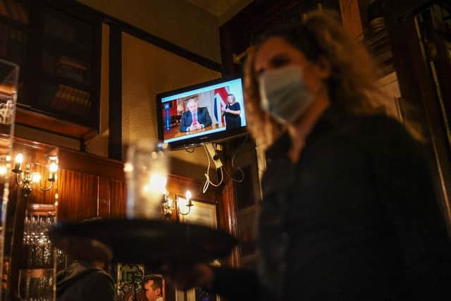 A barmaid walks past as British Prime Minister Boris Johnson makes a televised address to the nation inside the Westminster Arms pub on September 22, 2020 (Photo by Peter Summers/Getty Images)