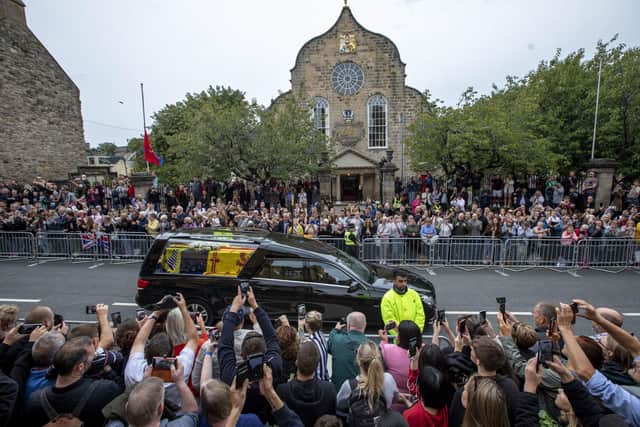 Members of the public gather on the Royal Mile at Cannongate Kirk in Edinburgh to watch the hearse carrying the coffin of Queen Elizabeth II, draped with the Royal Standard of Scotland, as it completes its journey from Balmoral to the Palace of Holyroodhouse in Edinburgh, where it will lie in rest for a day. Picture date: Sunday September 11, 2022.