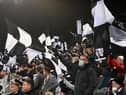 NEWCASTLE UPON TYNE, ENGLAND - DECEMBER 19: A Newcastle United fan wearing a face mask shows his support waving a flag during the Premier League match between Newcastle United and Manchester City at St. James Park on December 19, 2021 in Newcastle upon Tyne, England. (Photo by Stu Forster/Getty Images)