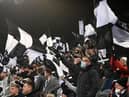 NEWCASTLE UPON TYNE, ENGLAND - DECEMBER 19: A Newcastle United fan wearing a face mask shows his support waving a flag during the Premier League match between Newcastle United and Manchester City at St. James Park on December 19, 2021 in Newcastle upon Tyne, England. (Photo by Stu Forster/Getty Images)
