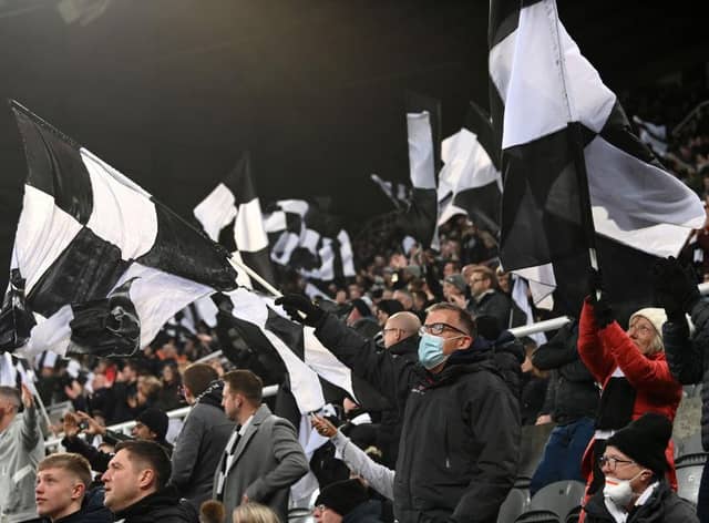 NEWCASTLE UPON TYNE, ENGLAND - DECEMBER 19: A Newcastle United fan wearing a face mask shows his support waving a flag during the Premier League match between Newcastle United and Manchester City at St. James Park on December 19, 2021 in Newcastle upon Tyne, England. (Photo by Stu Forster/Getty Images)