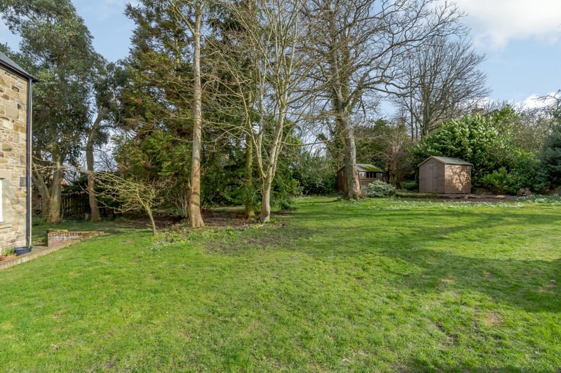 The property is set in around a third of an acre and features areas of level lawn interspersed with specimen shrubs and trees.
