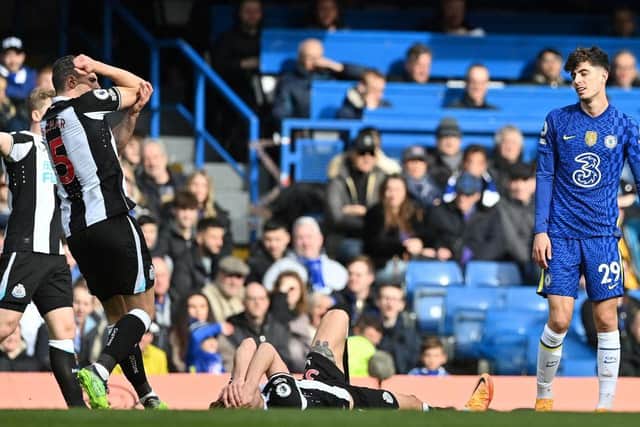 Newcastle United's Swiss defender Fabian Schar (L) points to his elbow as Newcastle United's English defender Dan Burn (C) lays on the pitch after clshing with Chelsea's German midfielder Kai Havertz (R) during the English Premier League football match between Chelsea and Newcastle United at Stamford Bridge in London on March 13, 2022. (Photo by JUSTIN TALLIS/AFP via Getty Images)